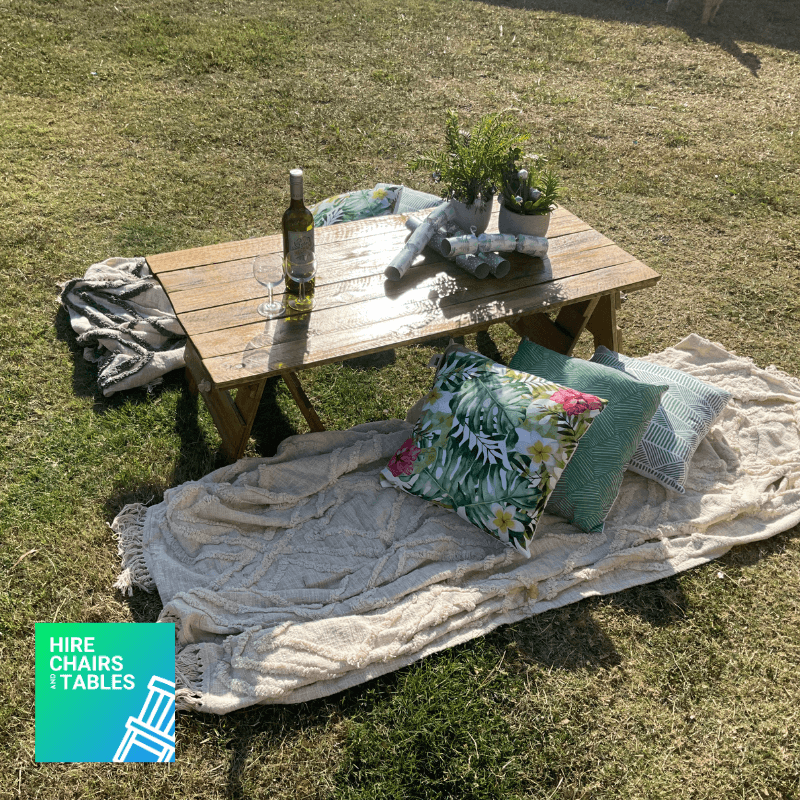 small table outside picnic with blankets and pillows